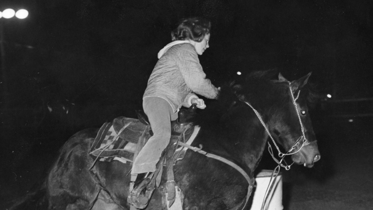 Reba rides horse around barrel 